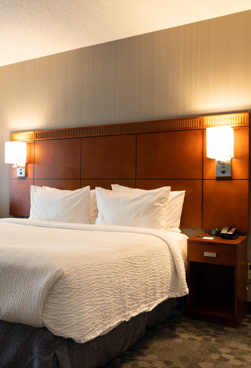 Hotel room with warm lighting and king size bed with white bedding.